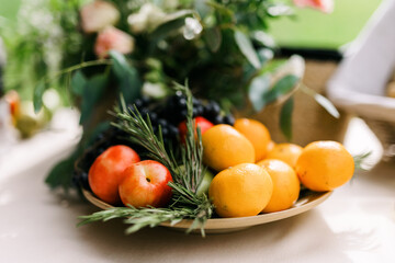 A fruit plate. Various fruits with rosemary on the table. Black grapes, nectarines, tangerines and green apples. 