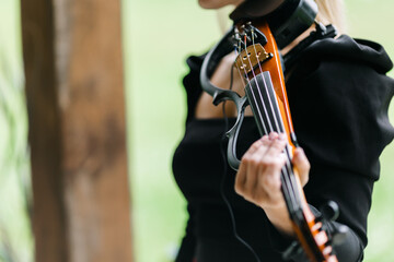 Fototapeta premium A girl playing an electronic violin. playing an instrument. violin close-up. The idea of classes during quarantine. The concept of music. 