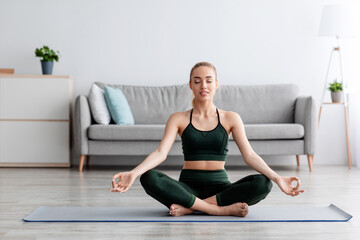 Calm caucasian pretty young blonde lady with closed eyes practicing yoga, breath, exercising at home