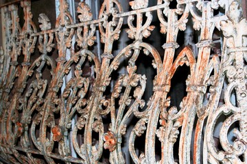 Antigua valla de hierro forjado de estilo bizantino, oxidada a lo largo de los años, proporciona seguridad con dibujos de curvas y flores, forma un bello diseño abstracto en la fachada de la casa