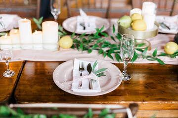 A beautiful outdoor wedding setting in pink flowers. plates and cutlery on a wooden table against a backdrop of greenery. On a Summer day 
a wooden reception table in the backyard, decorated with rose