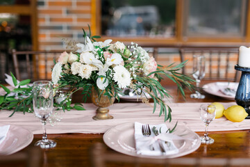 A beautiful outdoor wedding setting in pink flowers. plates and cutlery on a wooden table against a backdrop of greenery. On a Summer day 
a wooden reception table in the backyard, decorated with rose