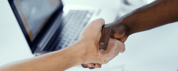 Obraz na płótnie Canvas African Hand and Caucasian Hand in Handshake, International Partnership, Racial Commonwealth, Unification, Friendship. Laptop Background. Close-up