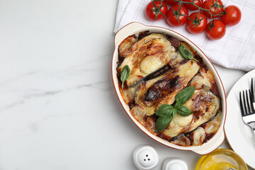 Delicious eggplant lasagna in baking dish on white marble table, flat lay. Space for text