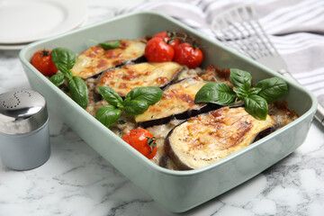 Delicious eggplant lasagna in baking dish on white marble table