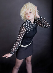 Curly girl - blonde in funny clothes like a clown on a black background