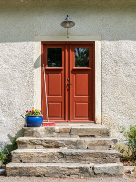 Old brown wooden entrance door with stone staris and flowers