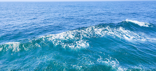 Trail on water surface on side of fast moving or sailing ship or boat