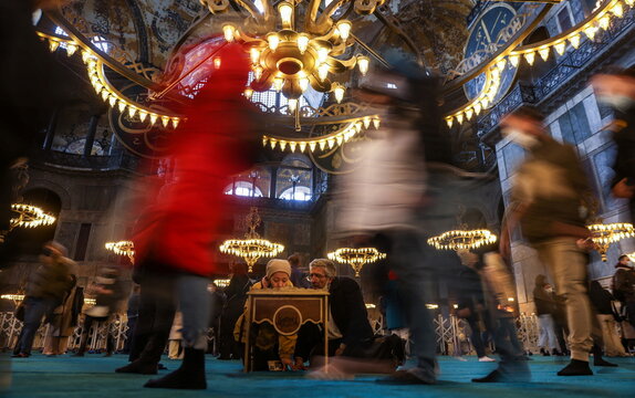 A man and a woman read Koran as tourists visit the Ayasofya-i Kebir Camii or Hagia Sophia Grand Mosque in Istanbul