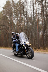 Obraz premium A couple rides a motorcycle on a forest road
