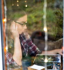 Pretty student girl spend time reading books in a cafe with lights running and customers walking on the background as they sit at a table with different books on it. 4K footage
