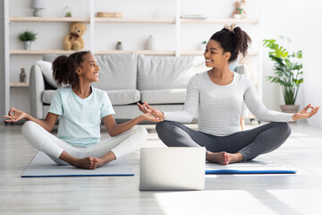 Athletic black mom and daughter having online yoga class