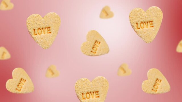 Flying and wiggle of different diameters heart-shaped yellow candies with label "Love"  on trending pink color gradient background. Romantic Love concept for mother's, St. Valentine's and women's day.