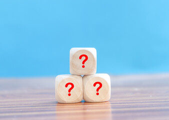 Wooden cube with Question mark icon on wooden table.