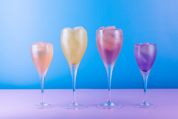 Various cocktail glasses with colorful drink on blue and pink background. Cocktail party concept
