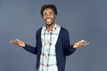 Joyful Man in Casual Clothes and Dreadlocks on his Head Smiles Broadly and Stands Isolated on a Gray Background. Double Sided Copy Space. Close-up - obrazy, fototapety, plakaty
