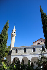 Fototapeta na wymiar old mosque in small turkish city Alacati on blue sky background