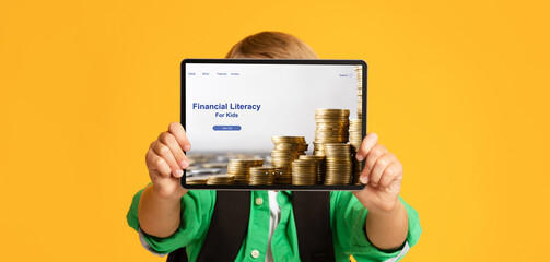 Unrecognizable boy holding tablet pc with Financial Literacy For Kids website in front of his face...