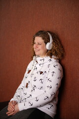 Frau in Sweater mit weissen Kopfhörern geniesst Musik, lächelt