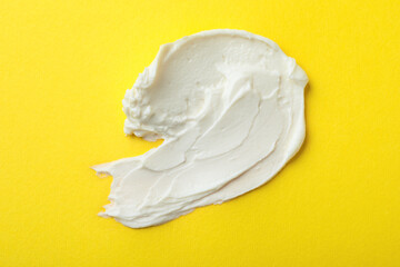 Smear of delicious cream cheese on yellow background, top view