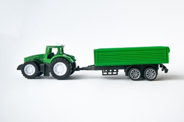 Toy plastic green tractor with trailer on white background