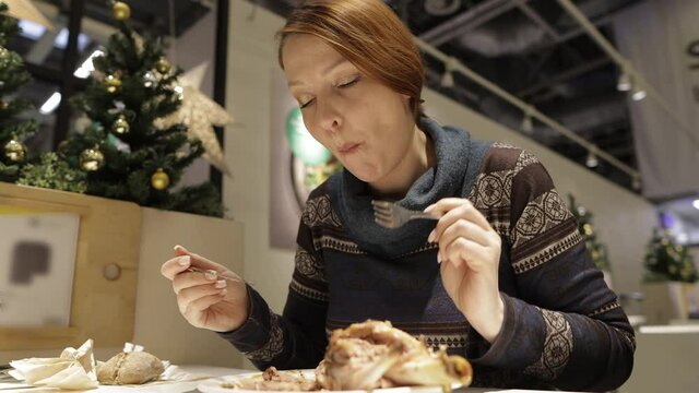 a woman eats fried pork knuckle with broccoli in a restaurant