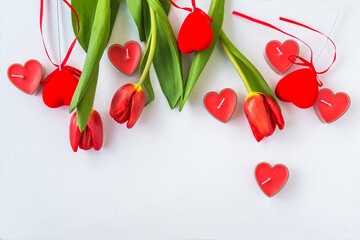 Valentine's day greeting card; Red tulips and candles shape heart on white background; space for text