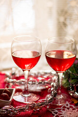 two glasses of red wine on a festive New Year's table against a light curtain
