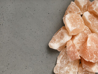 Background textured surface, large stones of pink himalayan salt, on gray background