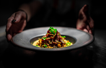 chef hand holding plate with food on kitchen in cafe 