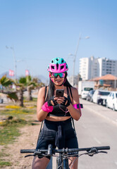 female biker staring at cellphone and smiling on the bikeway in the city
