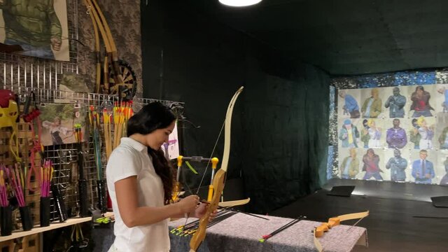 Girl with bow and arrow in her hands. Archer beginner.