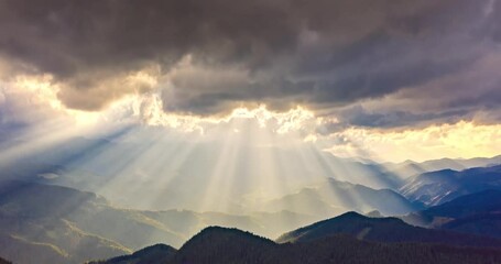 video of accelerated shooting from drone copter from a bird's eye view, time laps, clouds and rays of sunset quickly fly over the mountain peaks and valleys. Carpathians, Ukraine. - Powered by Adobe