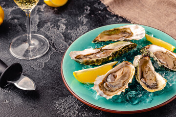 Opened fresh oysters on a blue plate, served with lemon and ice.