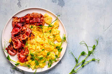 Traditional breakfast scrambled eggs with fried bacon