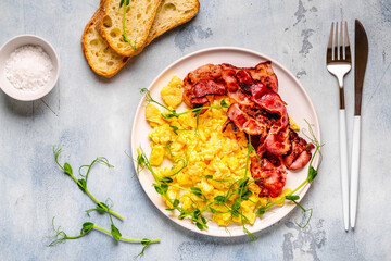 Traditional breakfast scrambled eggs with fried bacon