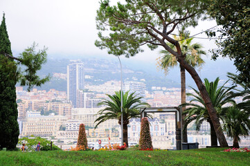 Fototapeta na wymiar Jardin des Pêcheurs. Park in Monaco-Ville. Modern buildings on the shore of the Port Hercules in the background. Monaco.
