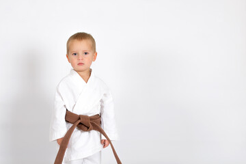 Little baby boy in karate kimono isolated on white background. The concept of martial arts, karate, judo,  sports since childhood, discipline. Defence concept with copy space.
