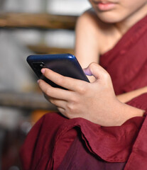 Asian little monk watching mobile smart phone. Concept of screen time.