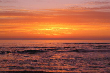 Fototapeta na wymiar ocaso en la playa, nubes y cielo anaranjado o dorado