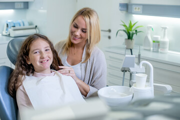 A young Caucasian woman and her cute pre-teen daughter visit a dentist for a regular teeth check-up at the stomatology clinic.
