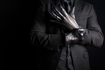 Portrait of Man in Dark Suit Pulling On Leather Gloves Menacingly. Threat of Danger and Violence.