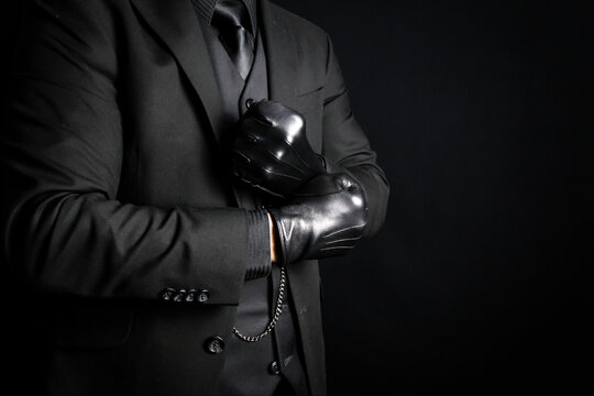 Portrait of Strong Man in Dark Suit Pulling on Black Leather Gloves. Mafia Hit Man or Criminal Gangster.