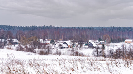 Rural landscape with village huts covered with white snow in winter.
