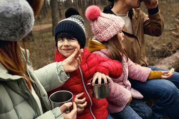 Happy family with hot drinks spending time together in forest