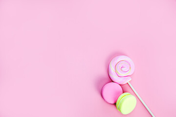 Candy sweets concept. Pink lollypop and donuts, macarons on pink background, copy space top view