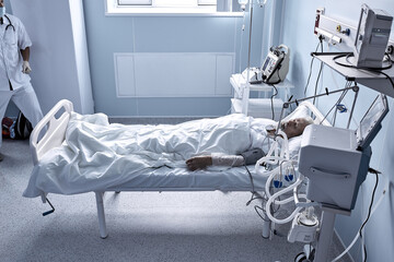 young injured man lying in bed hospital room resting from pain with tube in mouthm under dropper. caucasian sick guy is in bad health condition after suffering accident, in hospital ward, health care