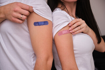 Young couple with bandage on their arms after receiving vaccination, Woman and man after vaccine wearing white t shirts at home , covid delta omicron vaccine concept