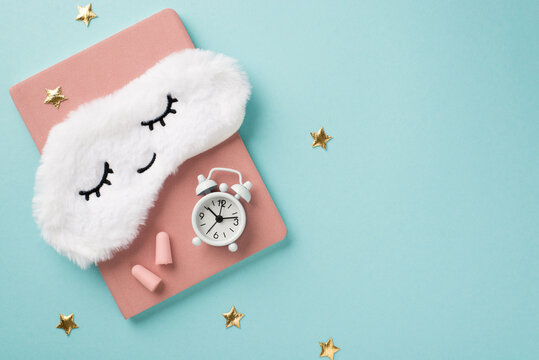 Photo of the light blue background pink notebook earplugs and mask for sleep in shape of cloud with clocks - Powered by Adobe