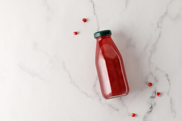 Pomegranate juice in bottle on marble background. Freshly squeezed. Vitamins. Mock up, top view.